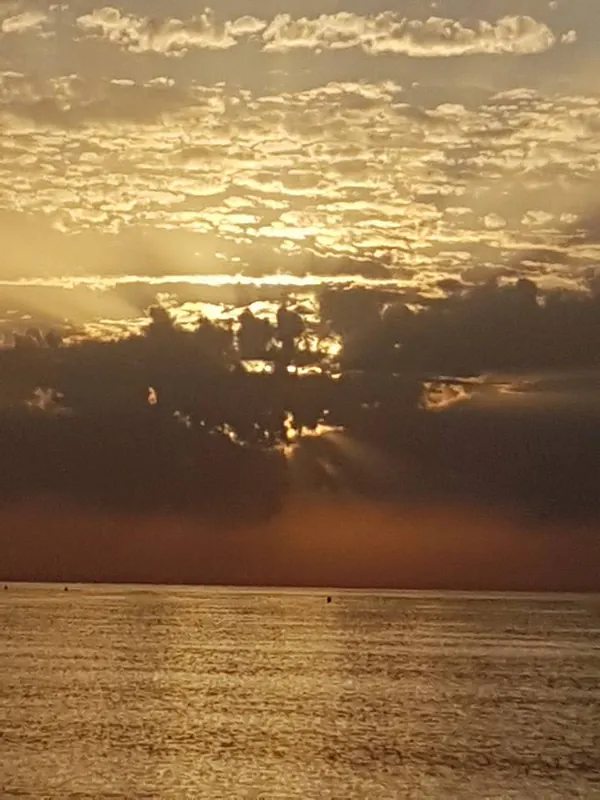 Nubes doradas con rayos de sol sobre un mar brillante