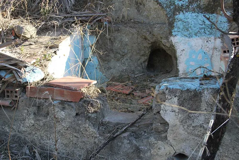 Restos de un lagar antiguo excavado en la roca, con paredes azules desconchadas