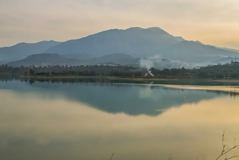 Montaña reflejada en las aguas tranquilas de un embalse al amanecer